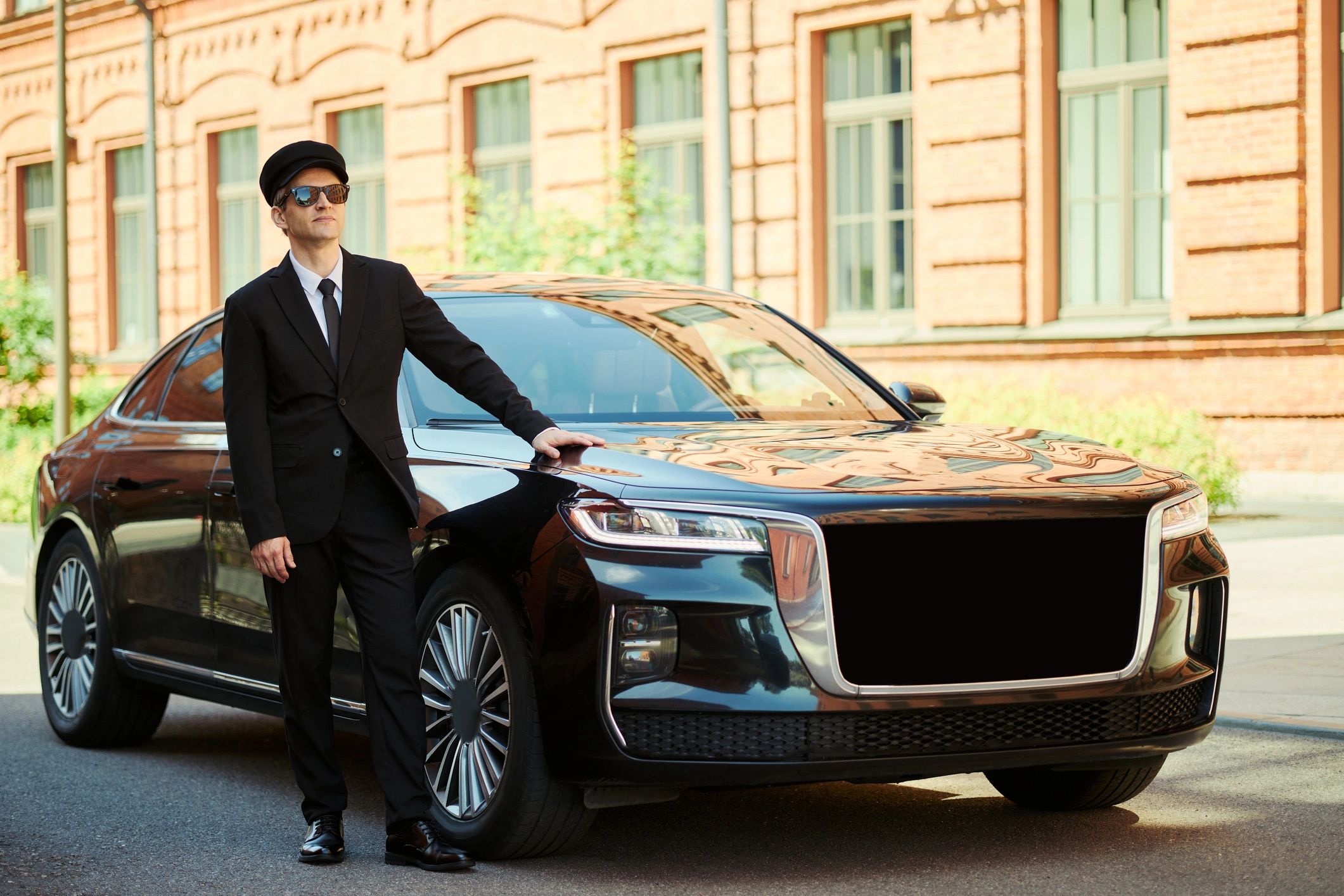 Professional chauffeur beside a luxury sedan
